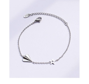 Detailed macro view of silver paper plane and hollow star charms on titanium steel bracelet
