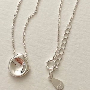 Detail view of S925 sterling silver necklace featuring a concave disc pendant on warm paper