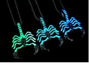 Luminous scorpion pendant necklaces glowing in green and blue colors on black background