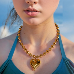 Golden ball chain necklace with large heart pendant on female neck and collarbone