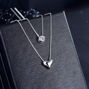 Silver layered necklace with round clear gemstone and heart pendant on jewelry box