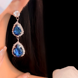 Close-up of model wearing silver blue teardrop crystal earrings with diamond pavé accents