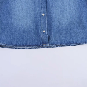 Details von gewaschenem blauem Denim-Hemd mit silbernen Knöpfen und klaren Nähten