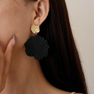 Detail of artistic geometric flower earring with matte black fan and gold textured disc