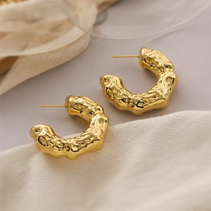Dettaglio macro di orecchini a cuore in oro 18K con trama lavica e perni in argento S925