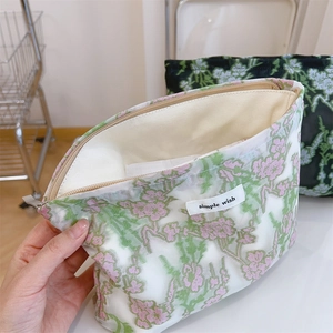 Floral embroidery cosmetics bag with large zipper opening and white woven label