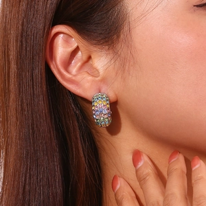 Close-up of thick C-shaped silver earrings with colorful rhinestones on a female model