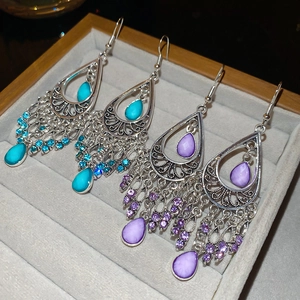 Detailed view of bohemian teardrop earrings with blue and purple stones on velvet