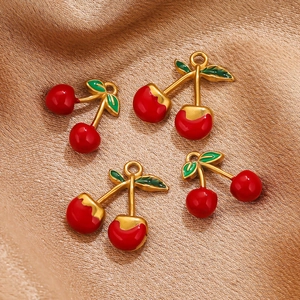 Détail de pendentifs cerises en émail rouge et tiges dorées sur soie champagne
