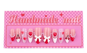 Detail of handmade press-on nails featuring 3D white bows, red hearts and pearls in size M