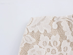 Close-up of white floral lace fabric texture with fine mesh and nude lining detail