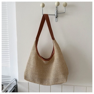 Close-up of woven straw texture and brown leather strap on a stylish summer tote bag