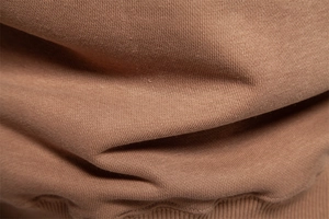 Macro detail of brown knit sweater fabric showing thick texture and ribbed hem finishes