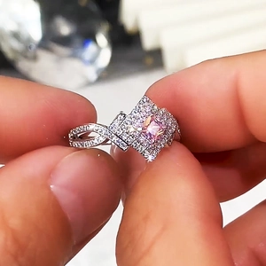 Macro shot of square pink zircon ring with criss-cross band on female finger