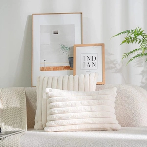 Close-up of beige faux fur striped pillows on a fabric sofa in a cozy interior setting