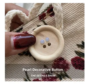 Detail of pearl decorative button on beige corduroy bag with wooden accent and red berries