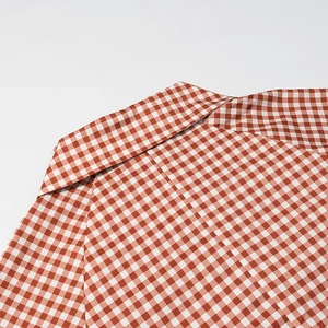 Gros plan sur le motif à carreaux rouge et blanc et les coutures du col en coton