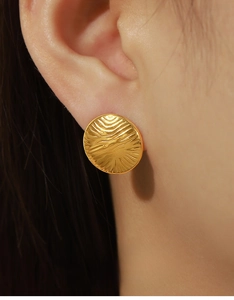 Close-up of gold-plated circular stud earrings with water ripple texture on model