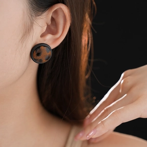 Gros plan d'un modèle portant une boucle d'oreille léopard ronde avec base noire vintage