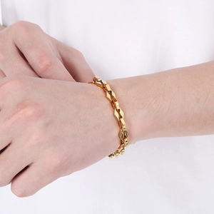 Bracelet chaîne à lèvres moderne en acier inoxydable doré porté au poignet d'un modèle