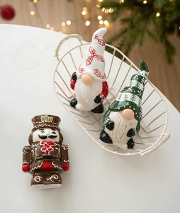 Ceramic Christmas nutcracker and gnomes figurines set on white background with festive lights