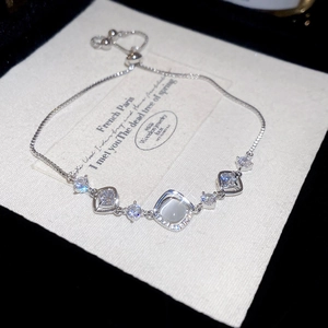 Macro detail of silver flower bracelet featuring zircon, cat eye stone, and box chain