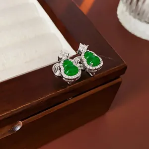 Gourd-shaped earrings with green stone and pavé zircon on a wooden jewelry box