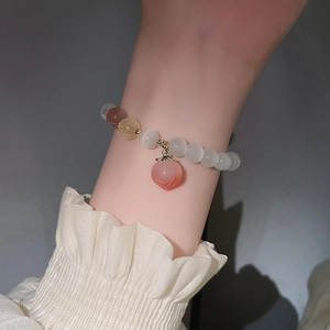 Nahaufnahme des Perlenarmbands mit transluzenten Steinen und Pfirsich-Anhänger