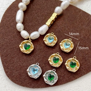 Detail of 14mm and 15mm heart charms with blue and green zircons in gold and silver plating