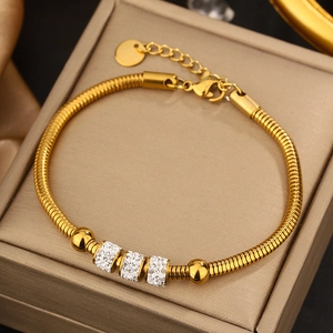 Detailed shot of golden snake chain bracelet featuring sparkling pavé crystal cylinders