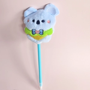 Blue ballpoint pen with cute plush koala topper and green scarf detail over pink background