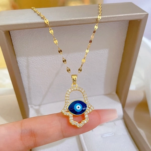 Gouden Hamsa Hand ketting met blauw boze oog en zirkonia's aan een verfijnde watergolfketting