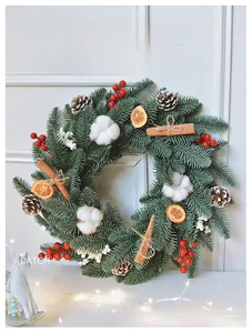 Detail of Christmas wreath with pine needles, red berries, cotton and cinnamon sticks