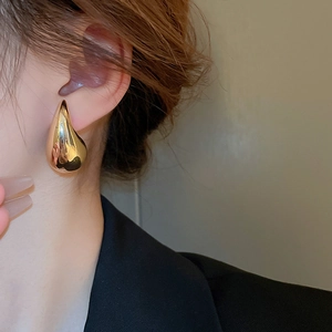 Close-up of elegant gold teardrop earrings worn by a model for a minimalist fashion look