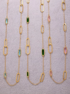 Detail of layered gold stainless steel necklace with faceted blue, pink, and green stones