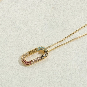 Gros plan d'un collier doré avec pendentif ovale orné de zircons arc-en-ciel colorés