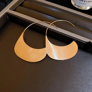 Détail de boucles d'oreilles dorées semi-circulaires avec finition en métal brossé poli