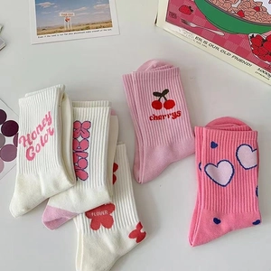 Dettaglio dei motivi a cuore rosa e ciliegie su calze in cotone bianco da donna