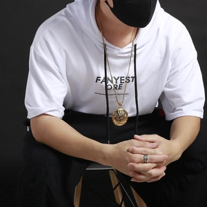 Detailed view of an ornate gold Indian-style chief pendant on a black streetwear hoodie