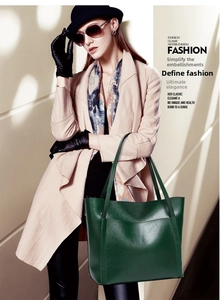 Detailed view of dark green oil-wax leather tote bag held by a model in a trench coat