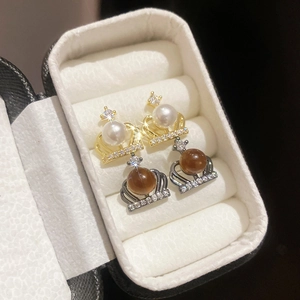 Close-up of crown stud earrings with pearls and rhinestones in gold and black settings