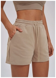 Close-up of beige drawstring sports shorts showing cotton fabric texture and pocket detail