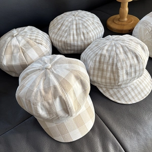 Flat lay of multiple linen plaid newsboy caps showcasing breathable texture and patterns