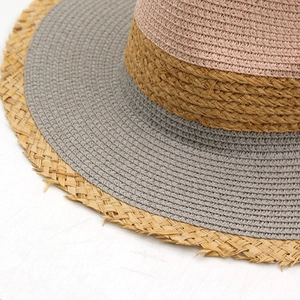 Dettaglio del cappello di paglia color-block con corona rosa e bordi sfilacciati