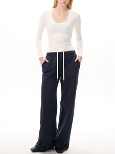 Détail d'un haut blanc à col en U avec manches longues et un pantalon large bleu marine