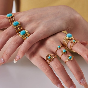 Detail of bohemian gold rings with turquoise stones worn together on fingers