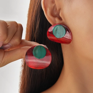 Detail showing marble texture red and green acrylic geometric drop earrings worn by model