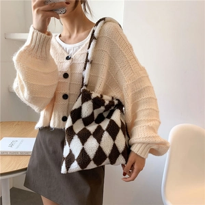 Brown and white checkerboard plush tote bag carried by model wearing a knit cardigan