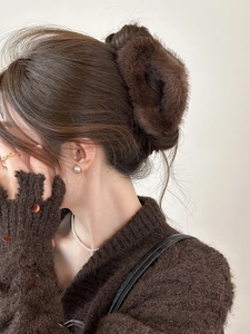 Vue détaillée de la pince à cheveux en fausse fourrure marron café portée par un modèle