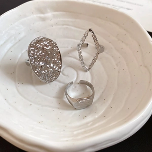Close-up of three-piece silver textured open ring set in a white ceramic bowl